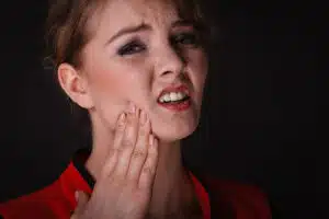 Young woman holding her jaw with pain from impacted wisdom tooth